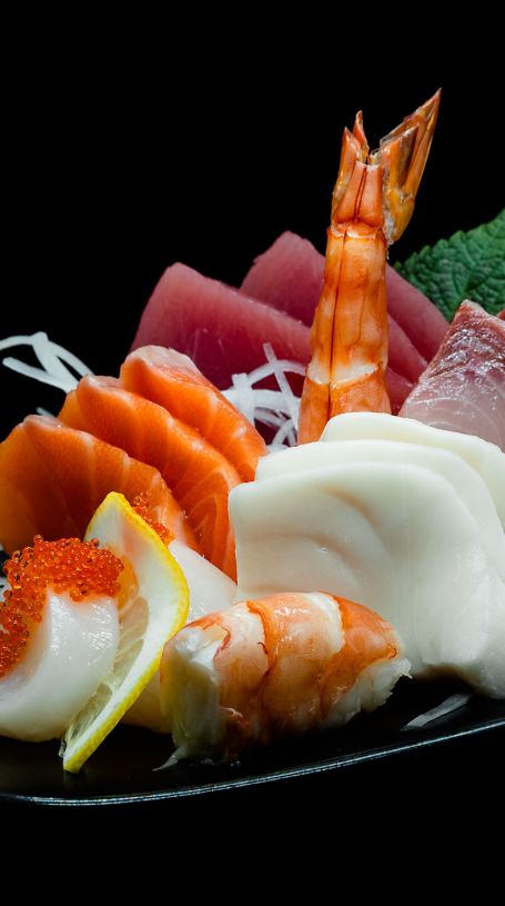 Ein elegantes Arrangement von frischem Sashimi Moriawase, bestehend aus verschiedenen Scheiben roher Fischsorten und Meeresfrüchten.